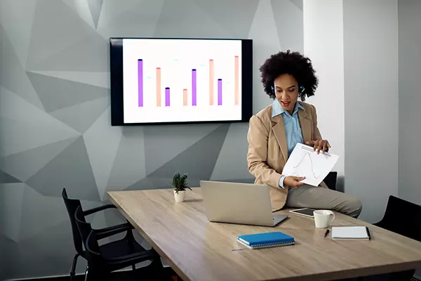 Mitarbeiterin erklärt einen Kunden über Video-Call den Ist-Stand des Unternehmens